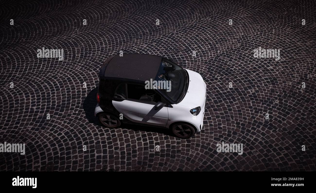 Un'auto intelligente bianca fotografata dall'alto su una strada lastricata di Roma con spazio per le copie. Foto Stock