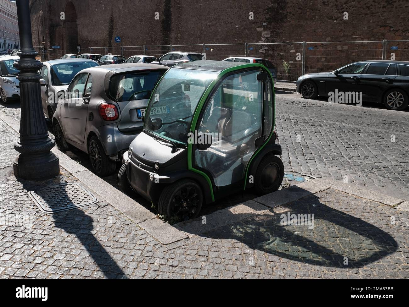 Una piccola auto elettrica Biro parcheggiata in uno spazio estremamente ristretto e con un'insolita angolazione sulle strade di Roma Italia. Foto Stock