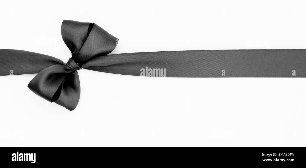 Arco a nastro satinato per confezione regalo di colore nero, isolato su sfondo bianco. Sfondo con arco a nastro su sfondo bianco. Foto Stock