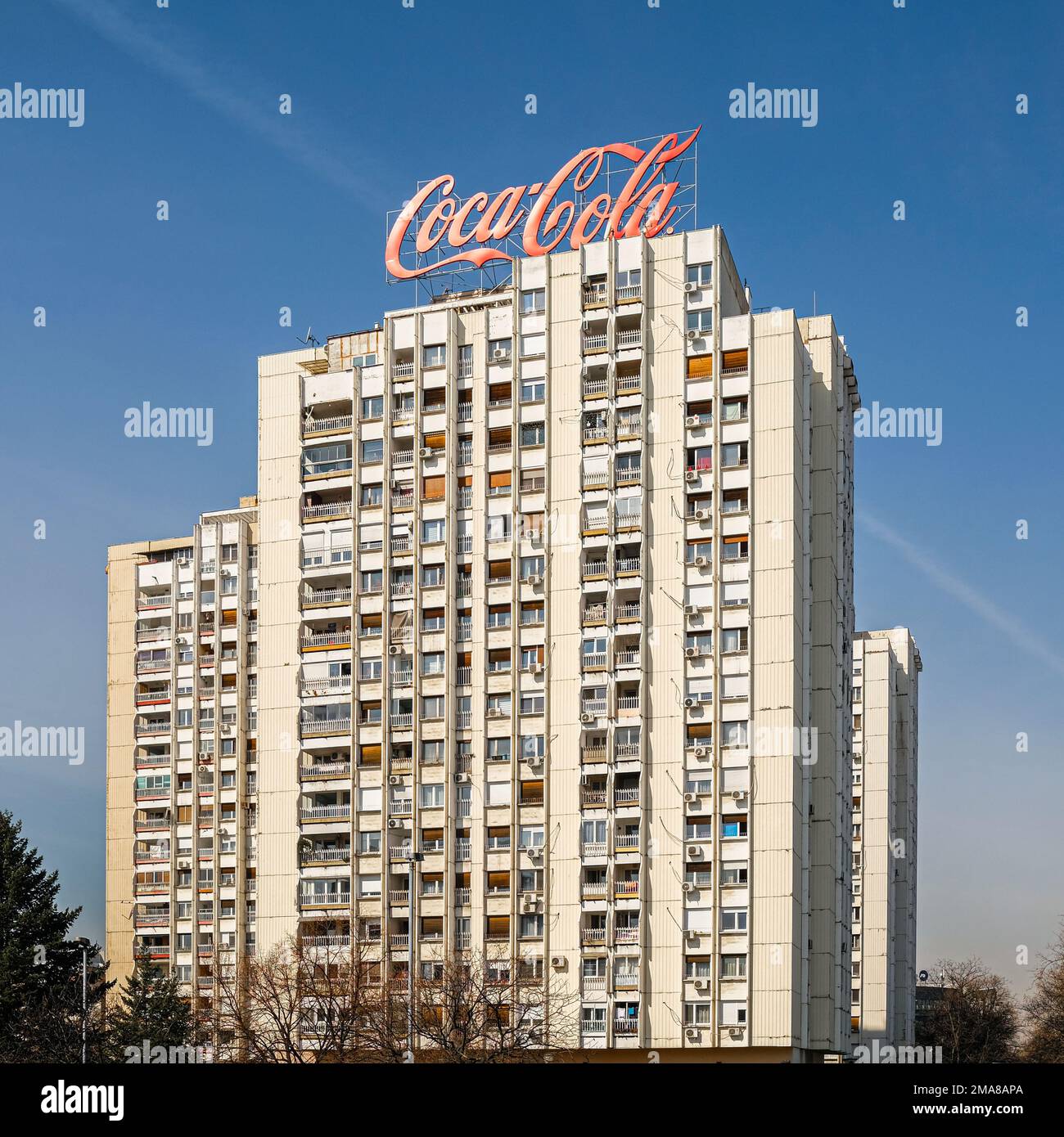 Edificio a torre con grande cartello Coca Cola in cima. Cielo su sfondo blu in una giornata di sole. Foto Stock
