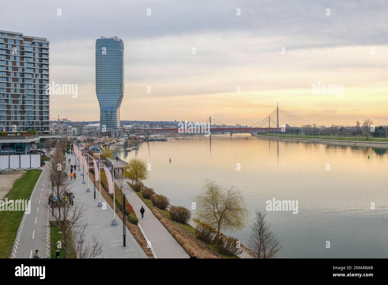 Il lungomare di Belgrado presenta la torre dell'appartamento BW Thalia dall'altra parte del fiume Sava in tarda serata. Foto Stock