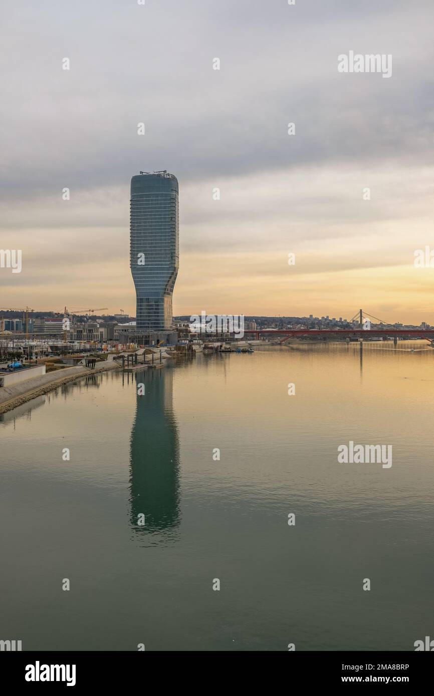 Il lungomare di Belgrado presenta la torre dell'appartamento BW Thalia dall'altra parte del fiume Sava in tarda serata. Foto Stock