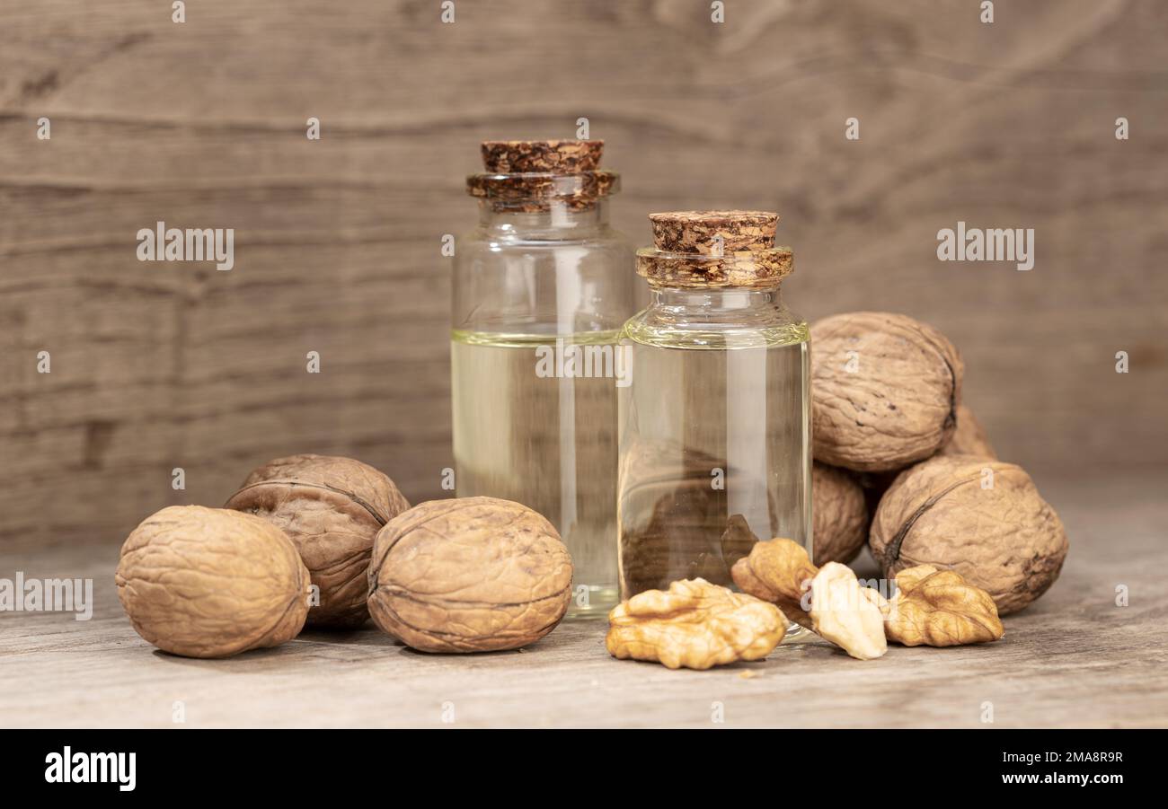 Olio di noce ancora vita. Bottiglia di vetro olio di noce su tavolo rustico di legno Foto Stock