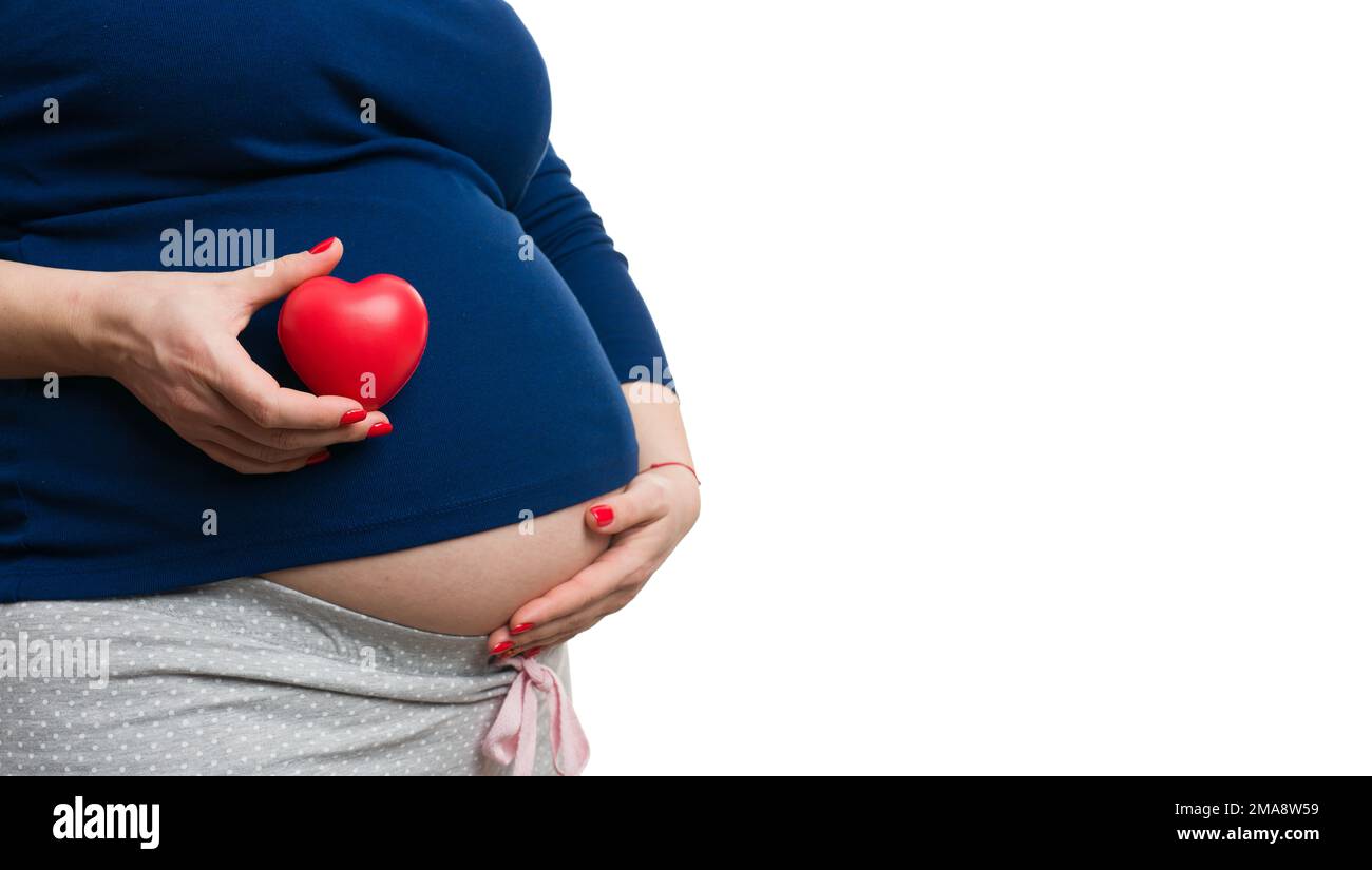 Primo piano di una donna incinta che tiene il giocattolo del cuore rosso con il copy-space come concetto di amore materno Foto Stock