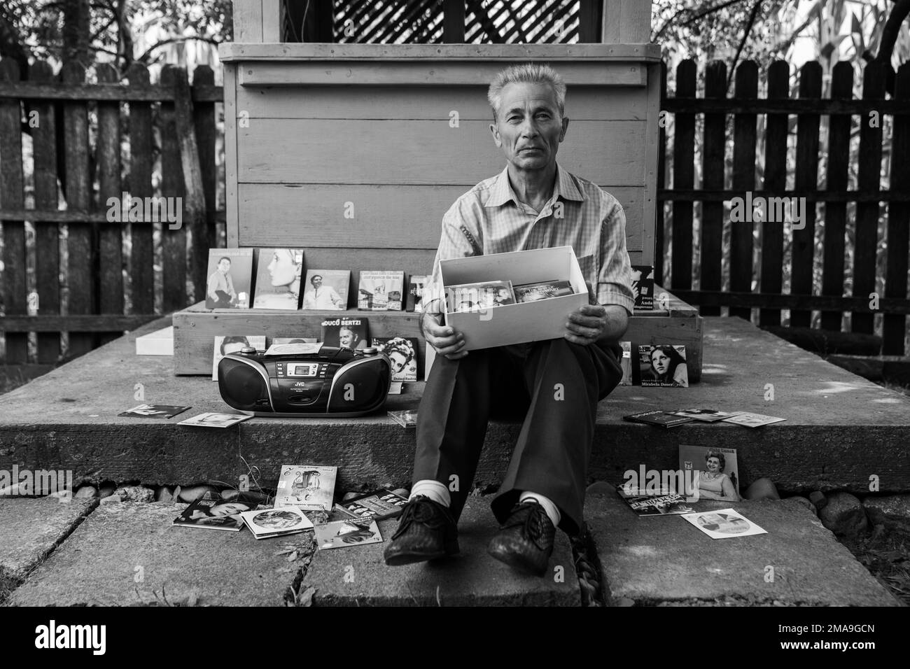 Un'immagine in scala di grigi di un vecchio maschio caucasico che vende musica CD vintage sul lato della strada Foto Stock