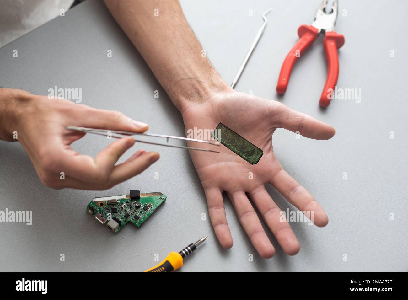 Concetto del braccio del robot. L'uomo mostra una mano biomeccanica protesica. Guy ripara la mano con l'attrezzo. Bioingegneria, transumanesimo, biohacking, cyborg umano Foto Stock