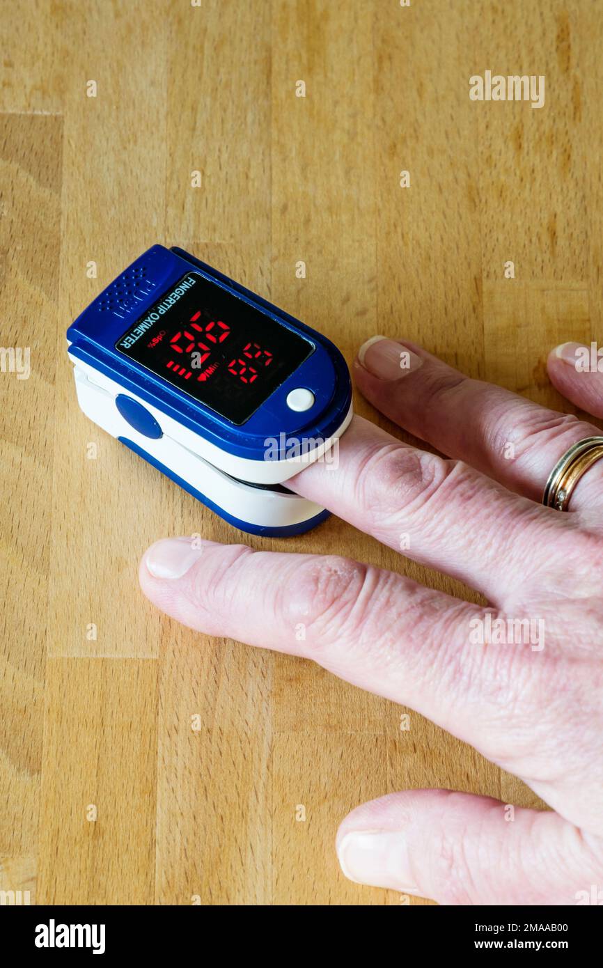 Donna che usa un pulsossimetro per misurare la quantità di ossigeno nel sangue. Foto Stock