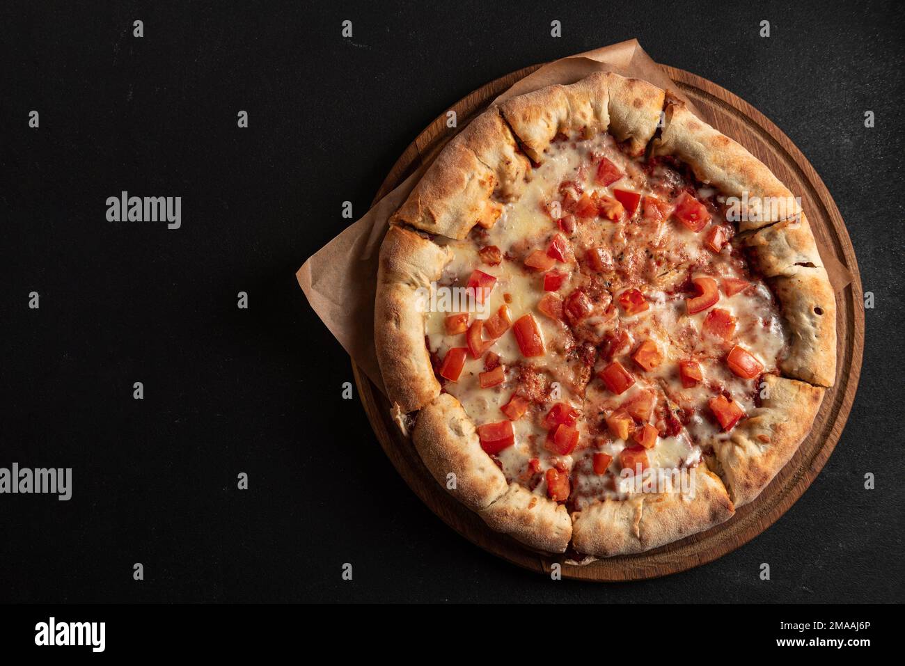 Pizza napoletana con spezie, pomodori e mozzarella su fondo scuro. Pizza margarita con mozzarella, salsa di pomodoro, spinaci spessi Foto Stock