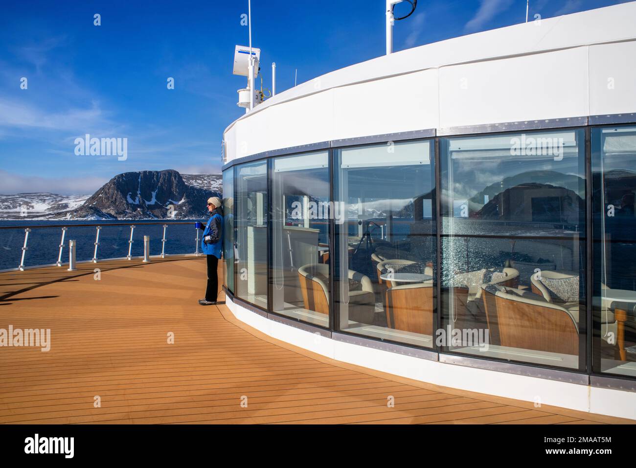 Ragazza turistica che si rilassa nel ponte principale della nave da crociera della spedizione Greg Mortimer nell'arcipelago di Svalbard, Norvegia artica. Foto Stock