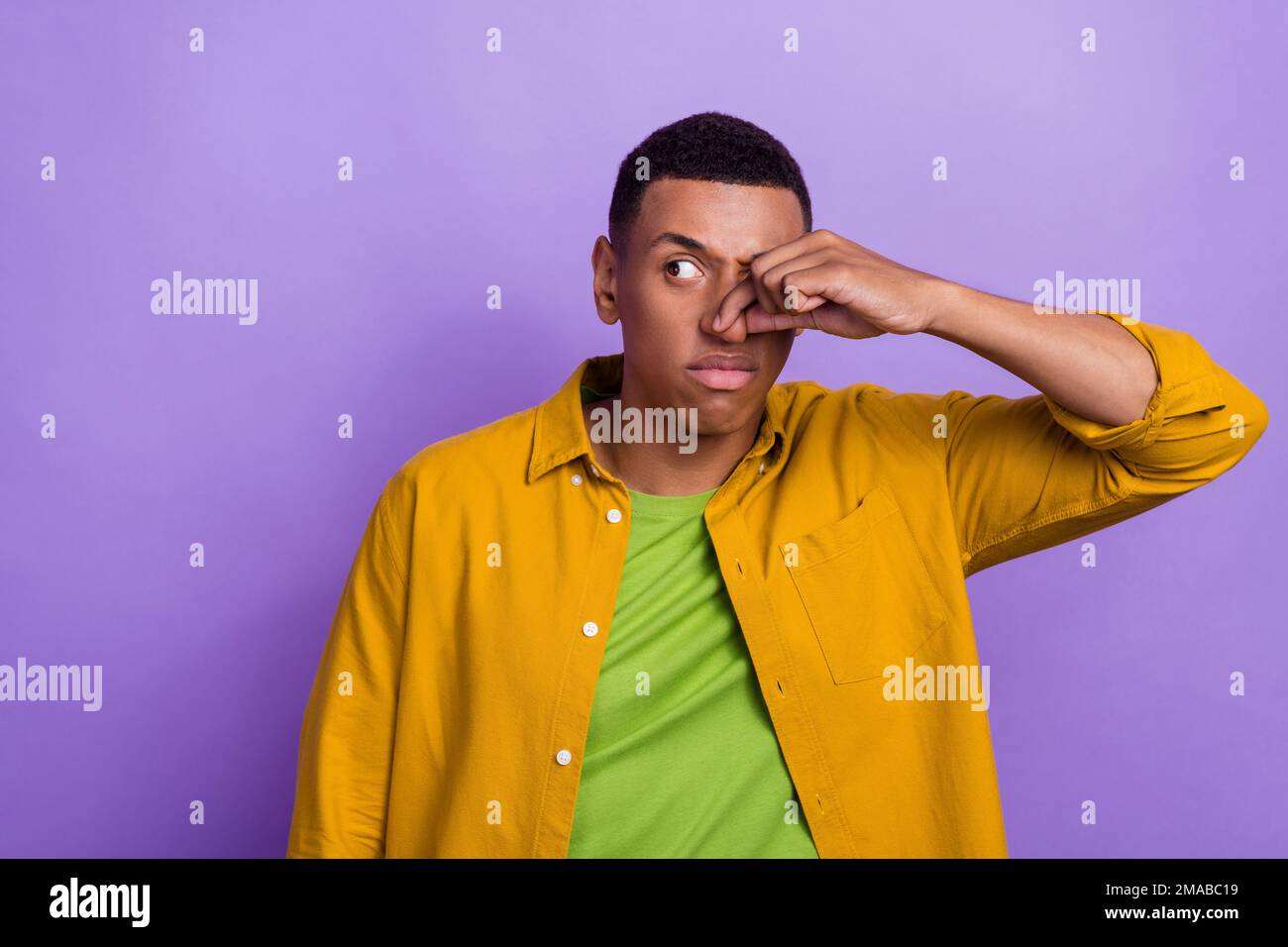 Foto ritratto di attraente giovane maschio naso chiuso evitare odore spazio vuoto vestito elegante vestito giallo isolato su sfondo di colore viola Foto Stock