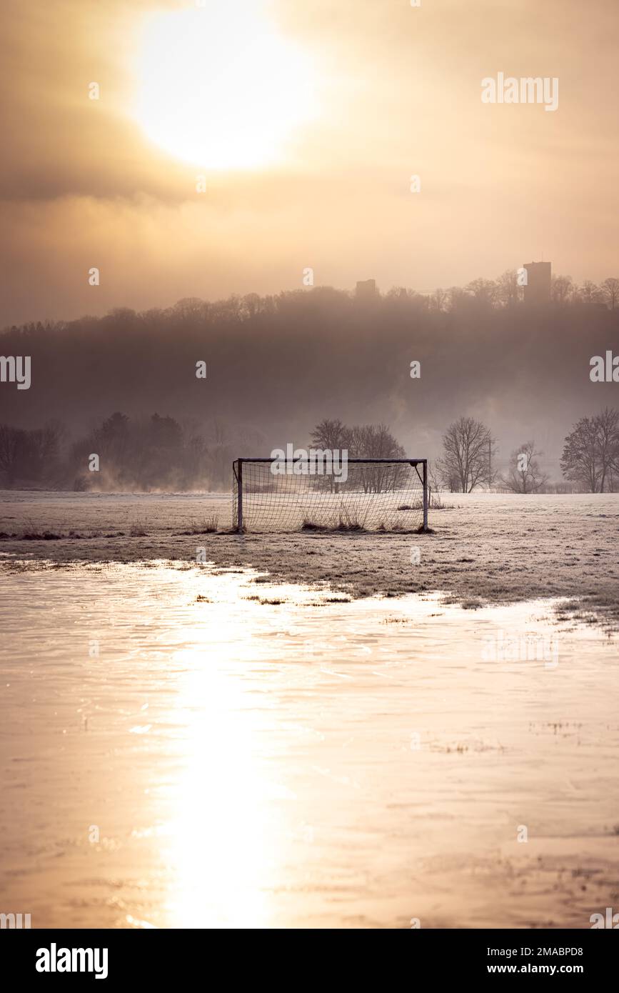 Calcio gol in una pozza ghiacciata nella calda luce di una mattina presto in inverno in Germania, con nebbia sullo sfondo Foto Stock