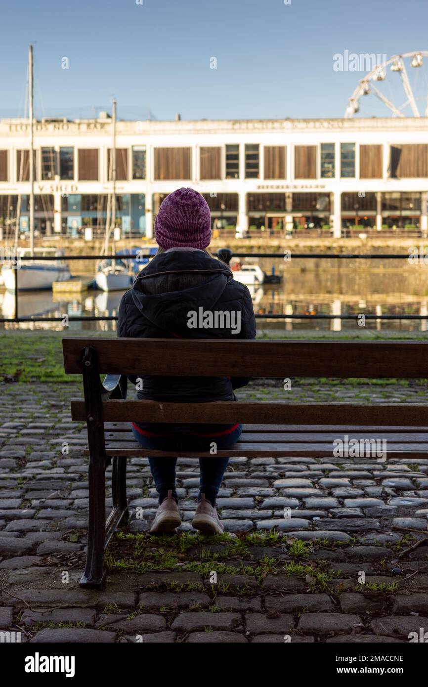 Donna seduta sola al porto di Bristol (Jan23) Foto Stock