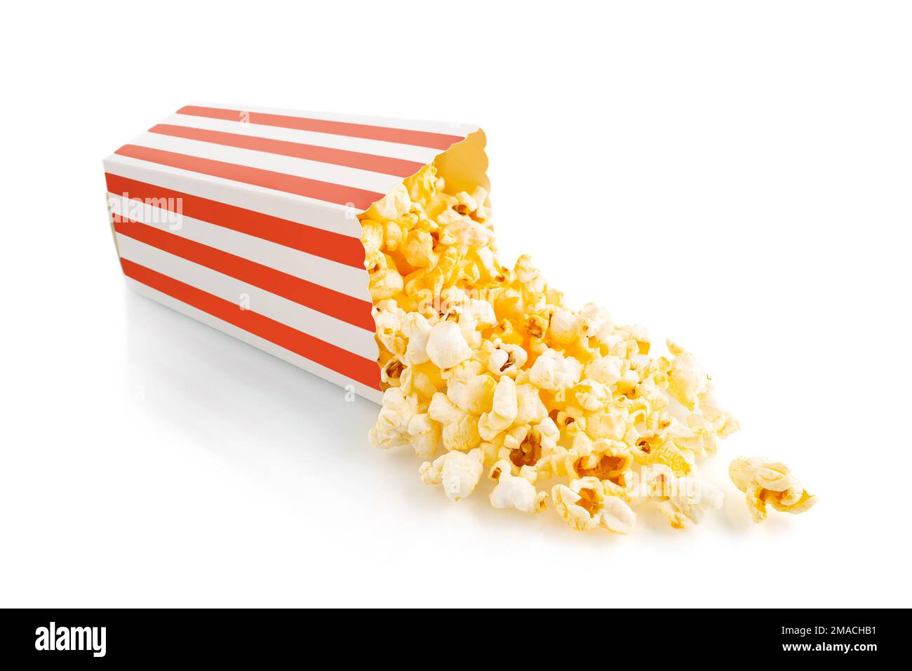 Gustoso popcorn al formaggio che cade da un secchio di cartone a strisce rosse, isolato su sfondo bianco. Dispersione di grani di popcorn. Film, cinema e ingresso Foto Stock
