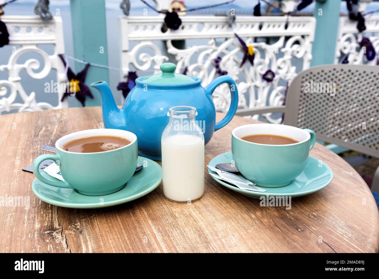 Due tazze di tè con teiera e latte al tavolo da picnic all'aperto Foto Stock