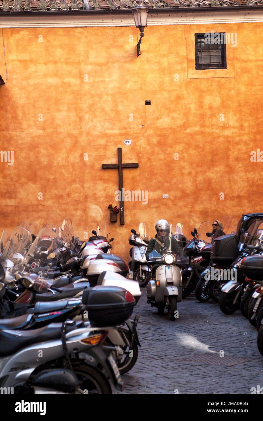 Un motociclista lascia il parcheggio accanto ad una chiesa cattolica a Roma. Italia. 10 novembre 2008 Foto Stock