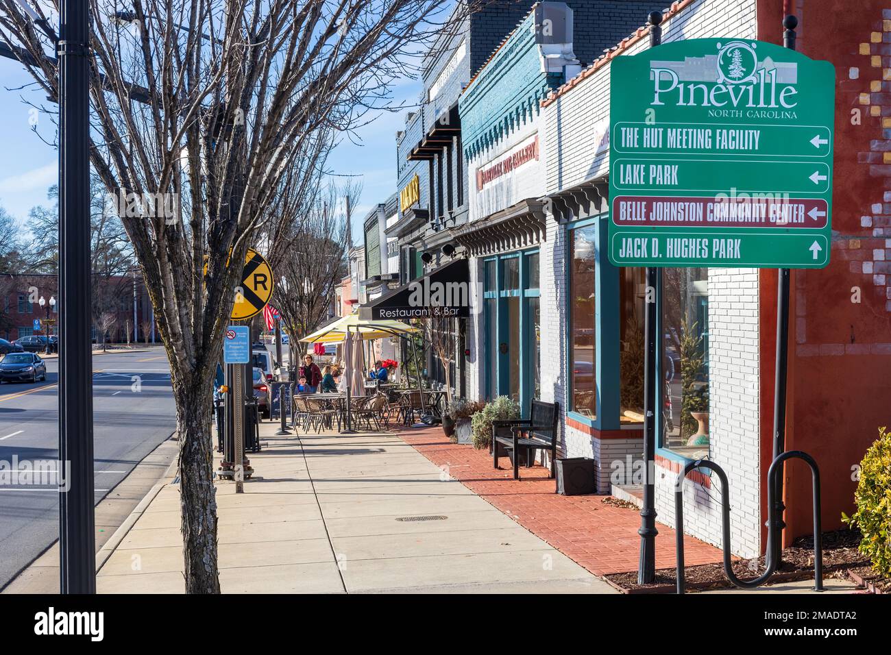 PINEVILLE, NC, USA-15 GENNAIO 2023: Vista sul marciapiede di Main Street, con i commensali al Margaux's an Christie's on Main. Sole, cielo blu giorno. Foto Stock