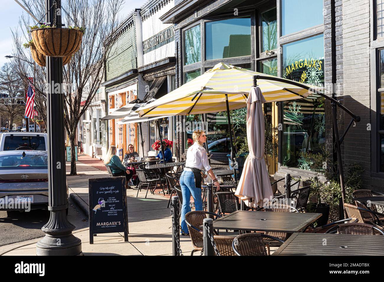 PINEVILLE, NC, USA-15 GENNAIO 2023: Vista sul marciapiede lungo Margaux's e Christie's on Main, con i clienti ai tavoli del marciapiede e una cameriera in chiaro Foto Stock