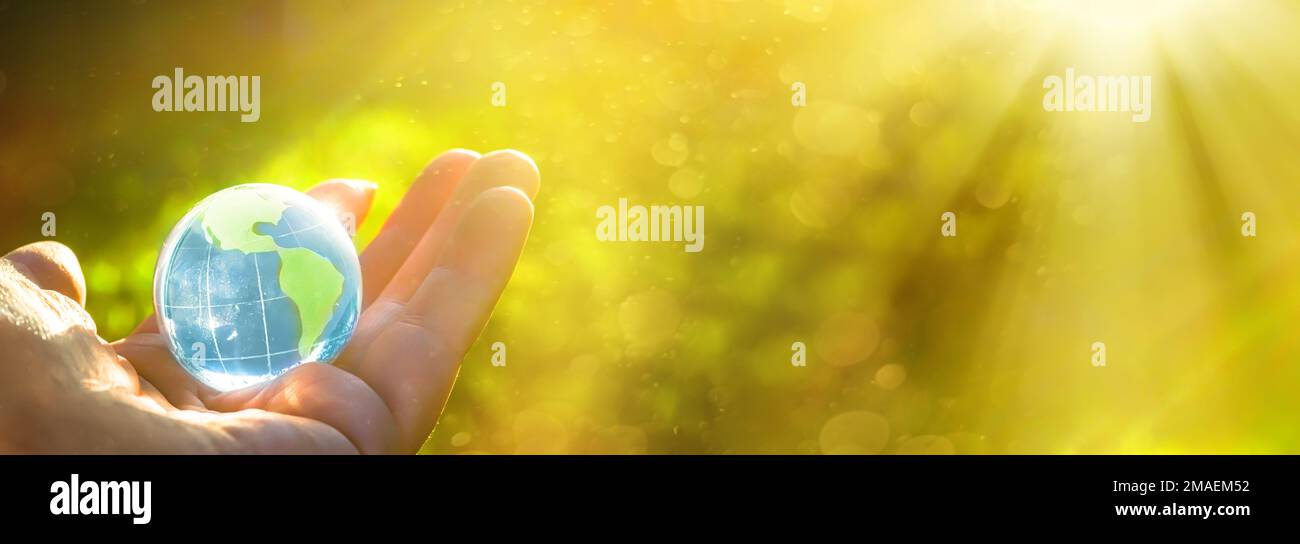 La mano tiene lo strato di cristallo sotto forma di globo. Concetto e tema della natura, protezione ambientale. salvare la terra o il pianeta. Giornata della Terra Foto Stock