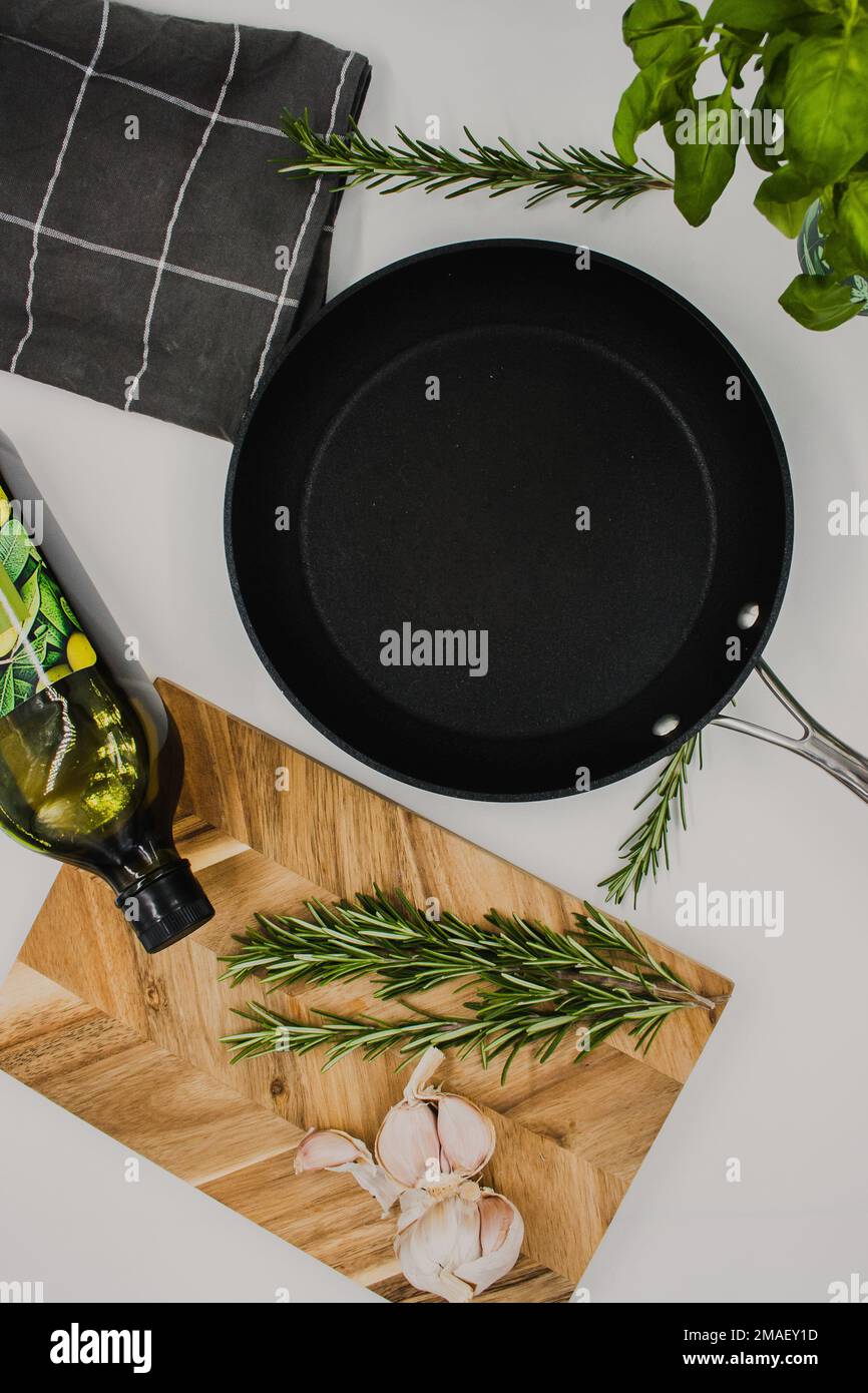 padella nera su fondo bianco con un asse di legno con aglio. giacitura piatta Foto Stock