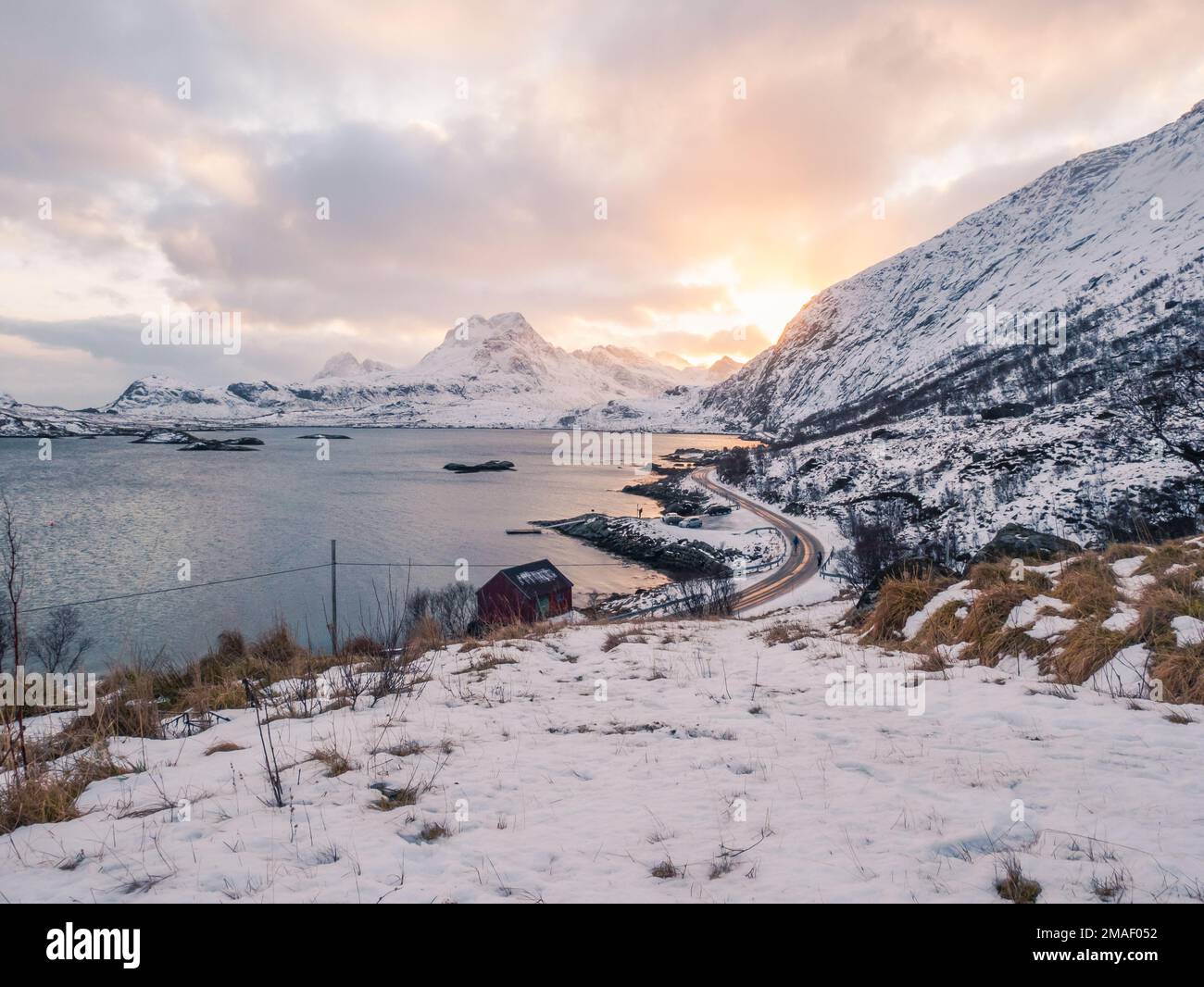 Sole che si trova dietro le montagne nel fiordo di Lofoten, Norvegia. Foto Stock