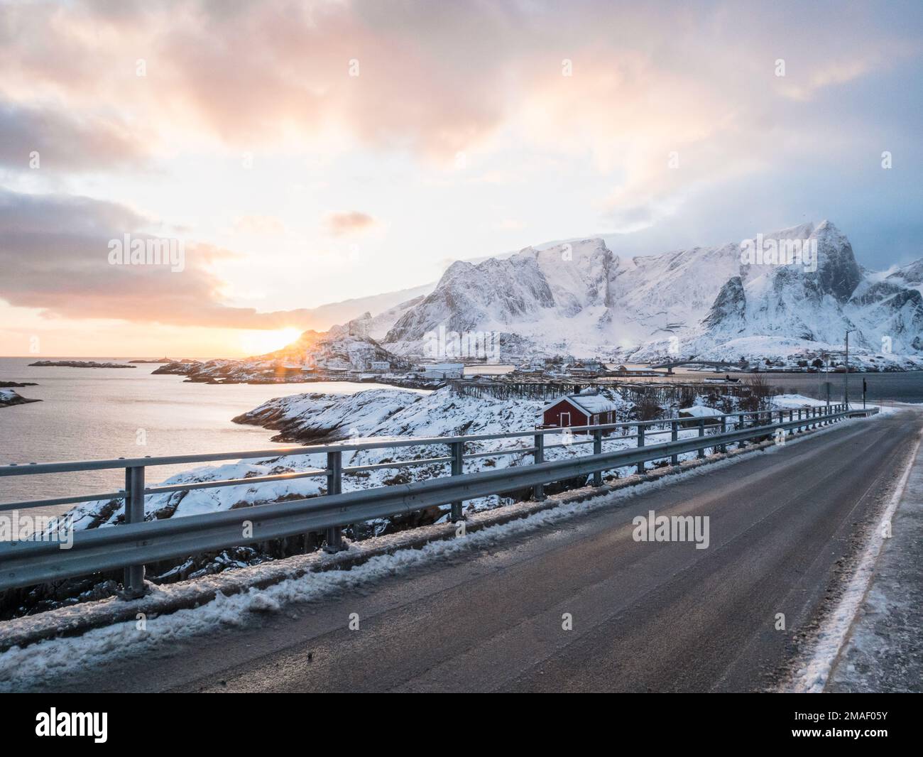 Sole che si trova dietro montagne e villaggi di Reine, Lofoten fiordo, Norvegia. Foto Stock