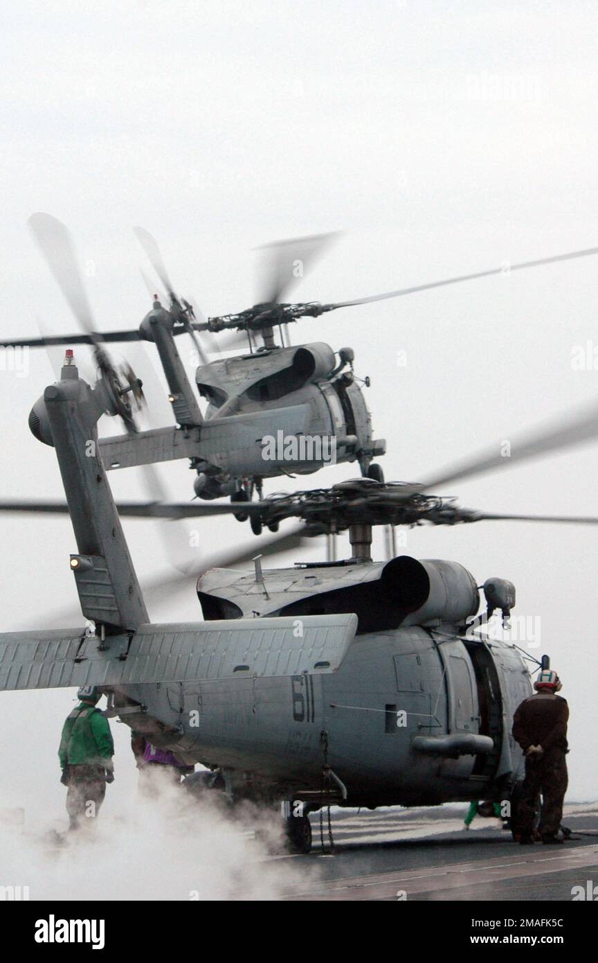 060529-N-9389D-192. [Complete] Scene Caption: One US Navy (USN) MH-60s Seahawk (Sea Hawk) multi-missione (guerra anti-sottomarina (ASW), guerra sottomarina (USW), guerra anti-superficie (AUSW), guerra speciale navale (NSW) inserimento, ricerca e salvataggio (SAR), ricerca e salvataggio di combattimento (CSR), rifornimento verticale (VERTREP), E le capacità di evacuazione medica (MEDEVAC) elicottero (sfondo) si solleva, come un secondo MH-60s Seahawk (primo piano) si prepara a scendere, dal ponte di volo della nave portaerei della classe USN Kitty Hawk, USS KITTY HAWK (CV 63). La USS KITTY HAWK è attualmente in corso su st Foto Stock