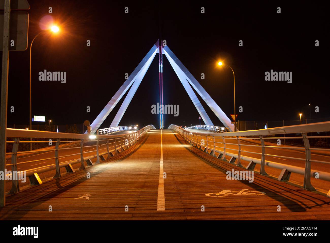 ponte a struttura metallica dove si possono vedere sostegni, pilastri, la sua pista ciclabile, auto e pedoni... Notte e illuminato Foto Stock