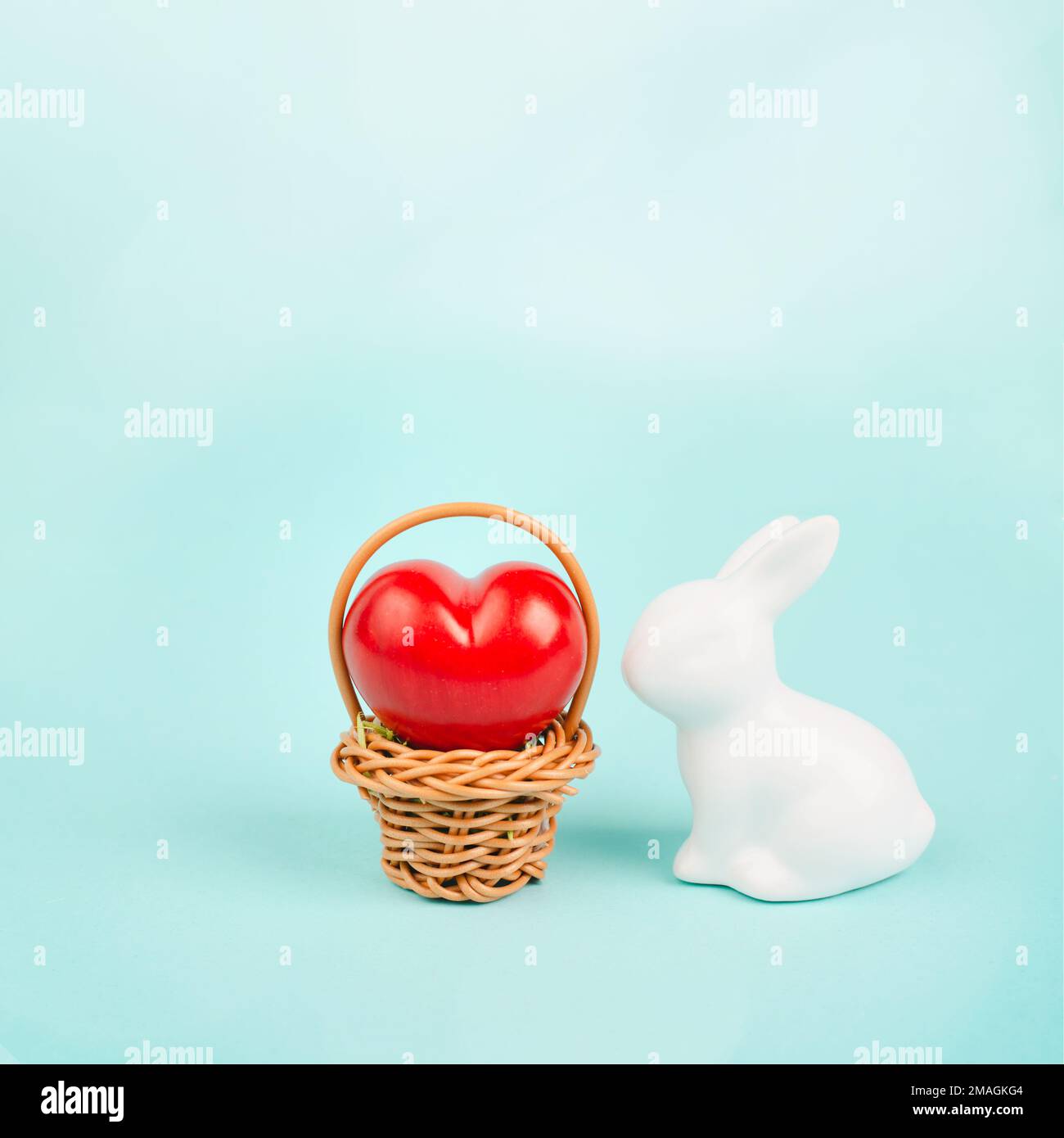 Cestino di vimini con un grande cuore rosso e un coniglietto di pasqua, coniglio porta dono d'amore, biglietto d'auguri per le vacanze Foto Stock