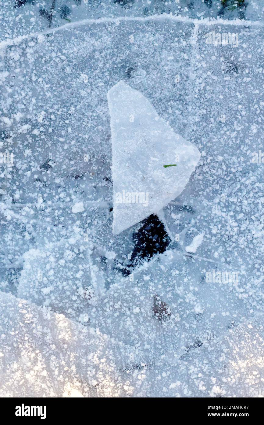 Primo piano di un pezzo di ghiaccio seduto in cima alla pudle congelata e rotta di cui era originariamente parte. Foto Stock