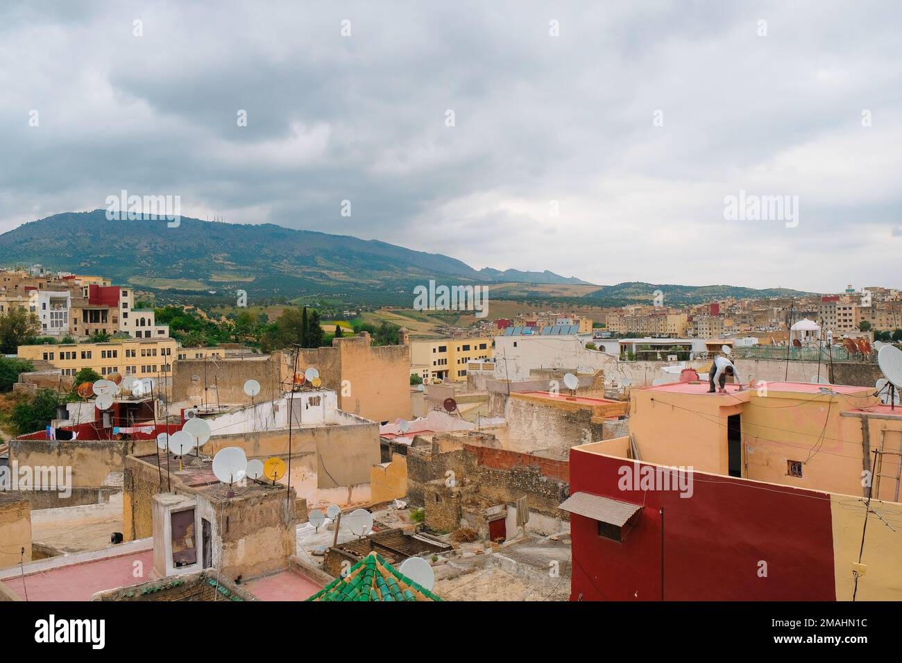 Fez, Marocco - Vista giornaliera dei tetti residenziali dalla medina di Fes el Bali. Edifici cittadini e montagne oltre. Sfondo di viaggio orizzontale, paesaggio urbano. Foto Stock