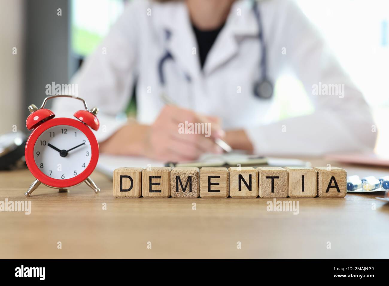 Demenza di parola e sveglia rossa sulla scrivania dei medici e medico sfocato in background. Foto Stock
