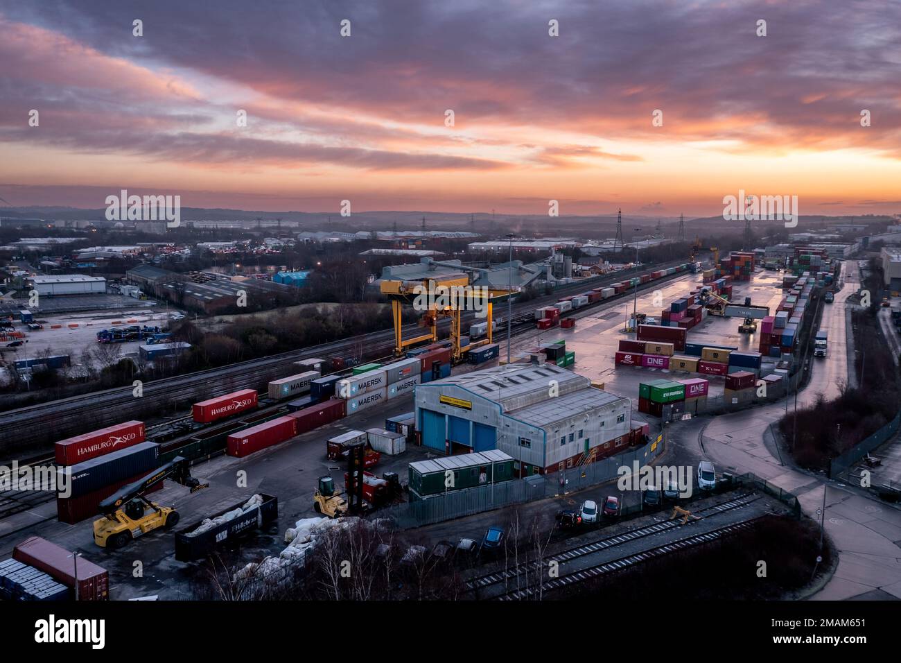 Vista aerea del terminale per container intermodale Freightliner di Leeds al tramonto con container per macchine pesanti per il trasporto su strada e su rotaia Foto Stock