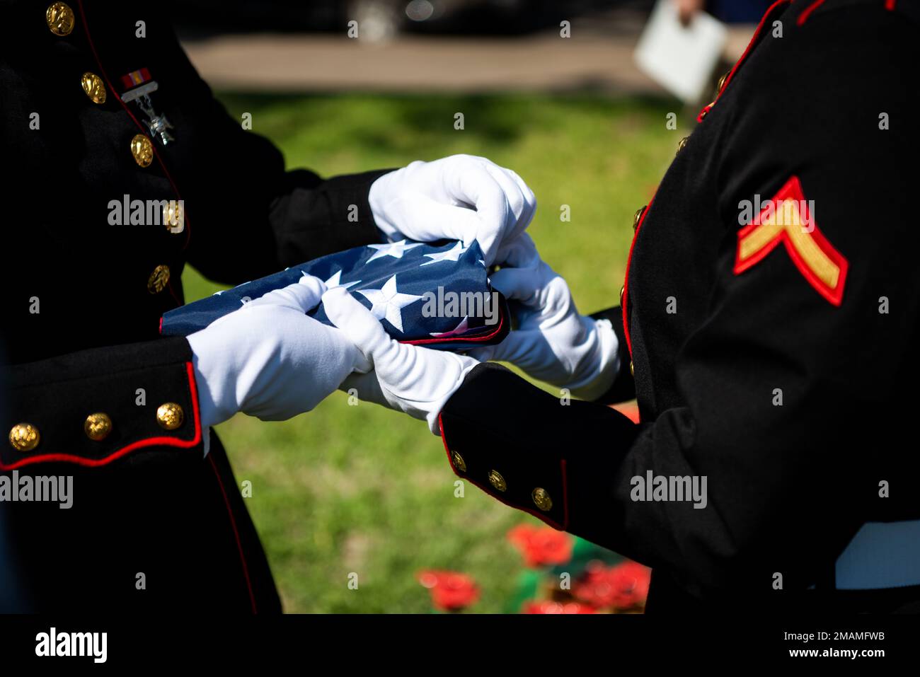 Due marines del distacco del corpo dei Marine Goodfellow piegano la bandiera americana durante un servizio di Memorial Day al Tom Green County Courthouse Lawn, San Angelo, Texas, 30 maggio 2022. La bandiera ripiegata è stata presentata alla signora Janet Worden, una consorte gold star presente alla cerimonia. Foto Stock