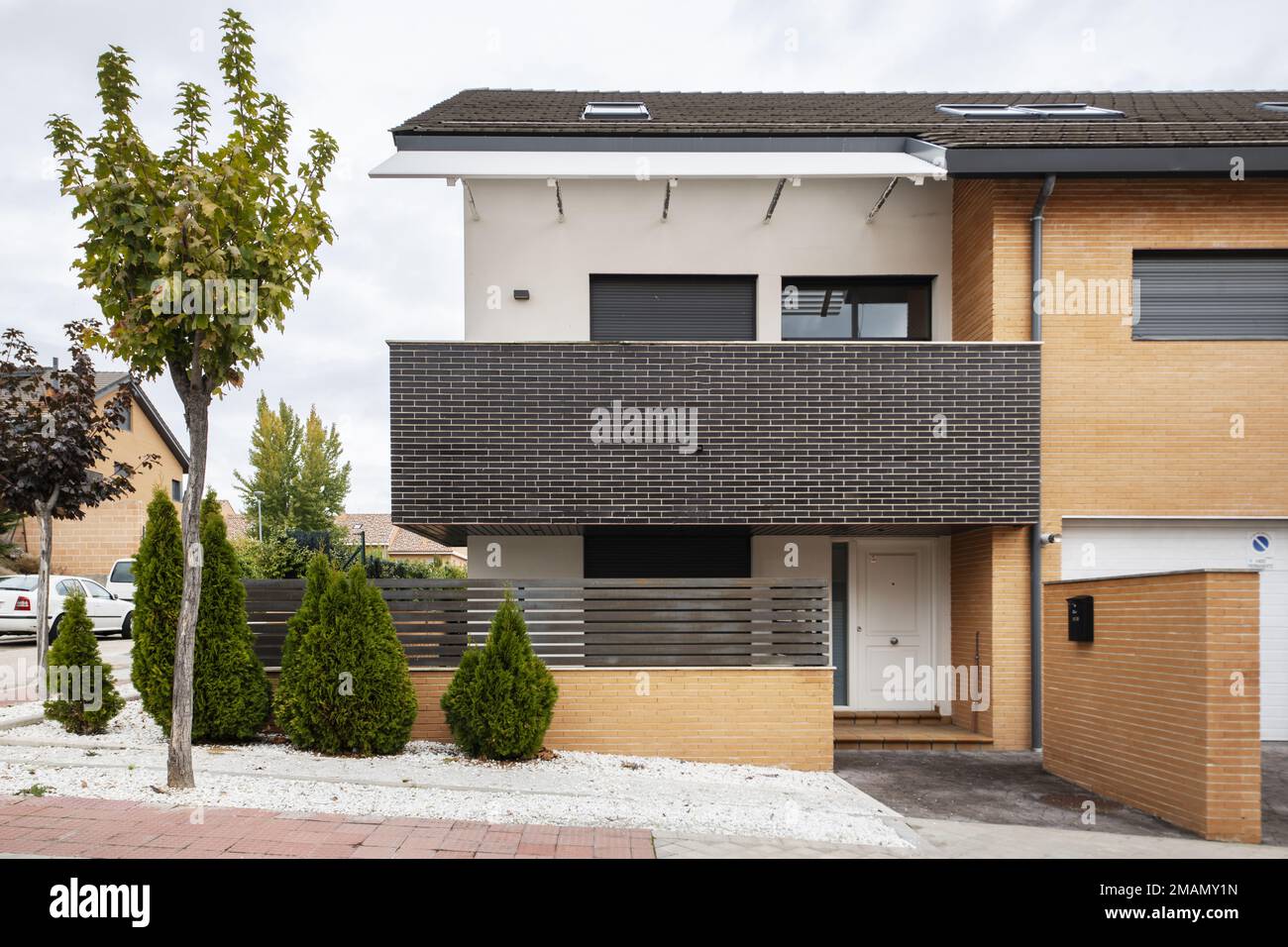 Facciate di strada di un'urbanizzazione con case semi-indipendenti singola-famiglia con alberi e siepi decorativi Foto Stock