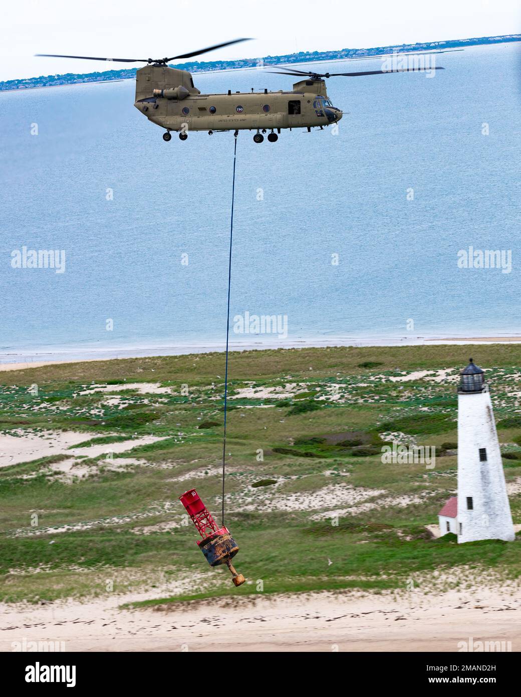 Un elicottero CH-47F Chinook del 2nd Battaglione, 104th Aviation Regiment, Connecticut Army National Guard, Sling carica una boa oltre un faro a Nantucket, Massachusetts, 1 giugno 2022. Chinooks dalla Guardia Nazionale dell'Esercito del Connecticut sono stati utilizzati nelle operazioni di recupero a causa del peso della boa (14.000 lbs.). Foto Stock