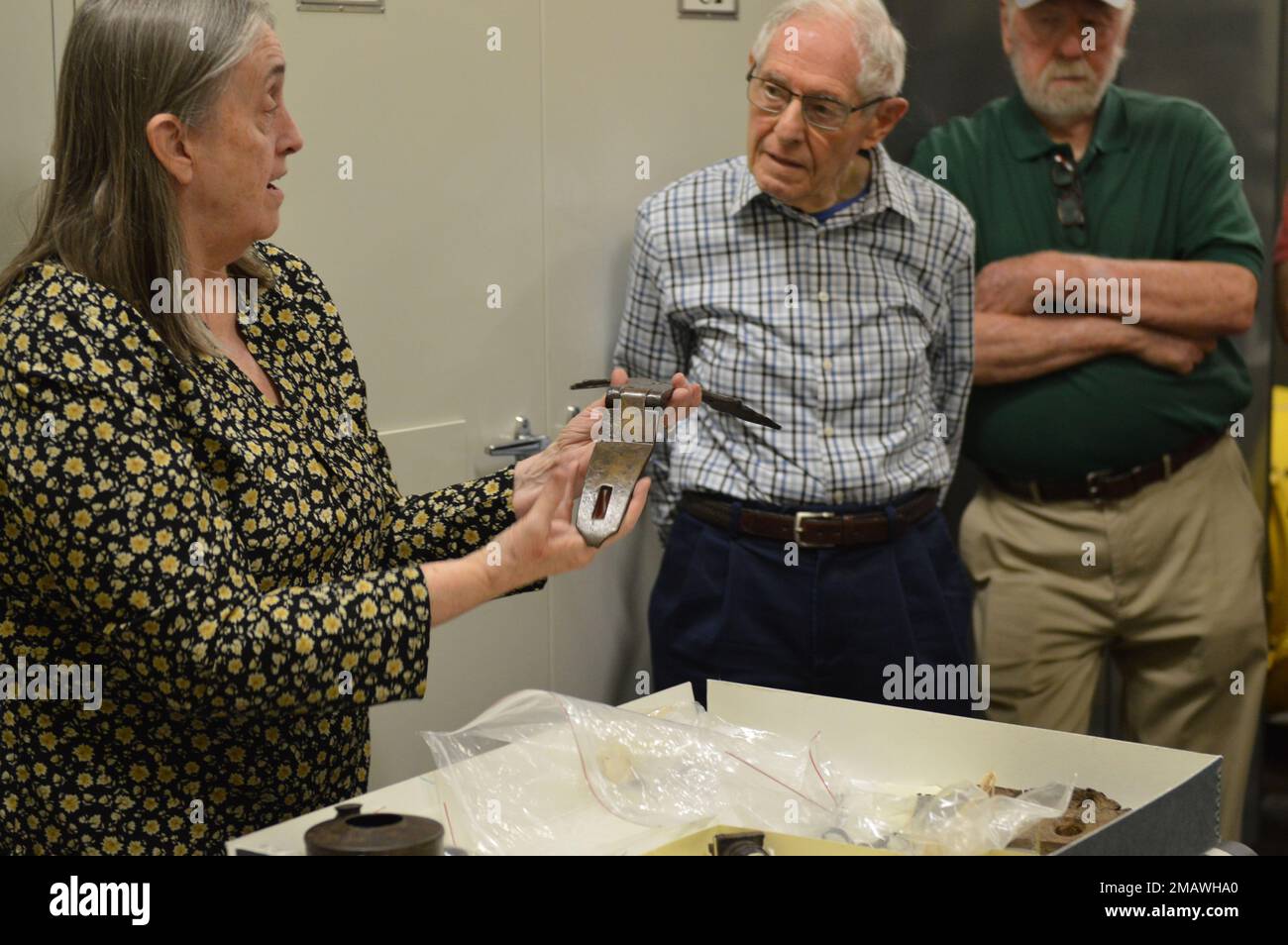 Tonia Deetz-Rock, vicedirettore e curatore del museo navale di Hampton Roads, si domanda da volontari del museo mentre mostra alcuni dei manufatti relativi alla USS Cumberland. I manufatti sono conservati presso la struttura di stoccaggio dei manufatti del museo a bordo della Naval Station Norfolk. La USS Cumberland, un anello di guerra nella Union Navy, affondò il 8 marzo 1862 durante una battaglia con il ram stordito confederato CSS Virginia. Il museo è il deposito per i manufatti recuperati dal Cumberland. Foto Stock