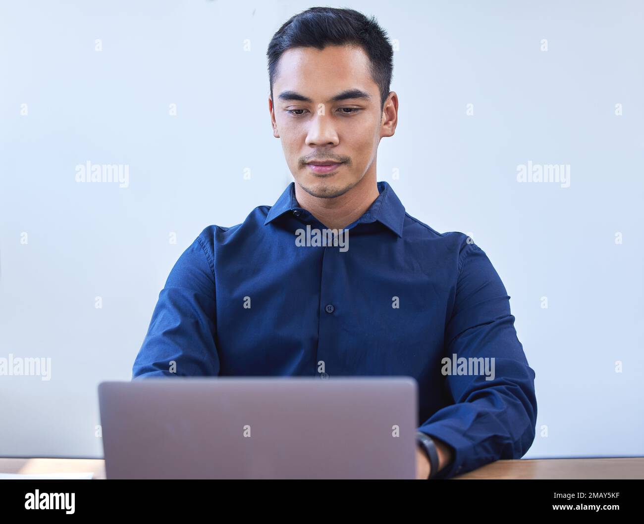 Il tipo che sempre ottiene tutto fatto in tempo. un giovane uomo d'affari che lavora su un computer portatile in ufficio. Foto Stock