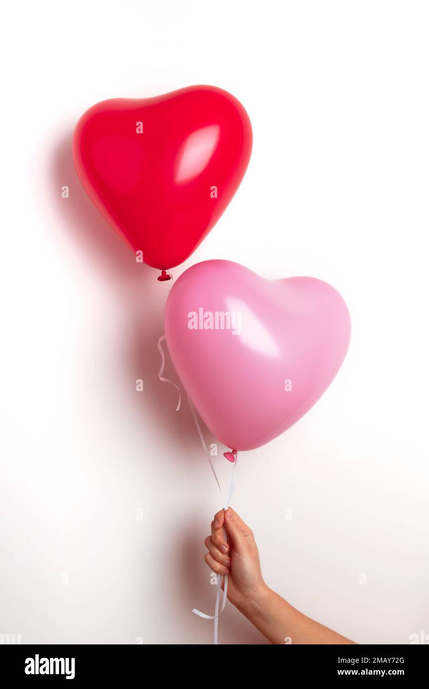 Palloncini gonfiabili di elio a forma di cuore per San Valentino sono  tenuti da una ragazza in mano. Vista frontale Foto stock - Alamy