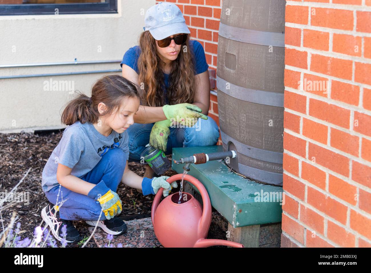 Defence Supply Center Columbus Environmental Division Chief Nicole Goicochea aiuta un bambino a riempire il suo annaffiatoio nel giardino del DSCC Columbus’ Child Development Center Giugno 8. Sette classi pre-K hanno partecipato al giorno della piantagione, ma tutte le classi al centro tendono al giardino ogni anno. Il giardino è una partnership congiunta con la Divisione ambientale DSCC ed è in sesta stagione. Foto Stock
