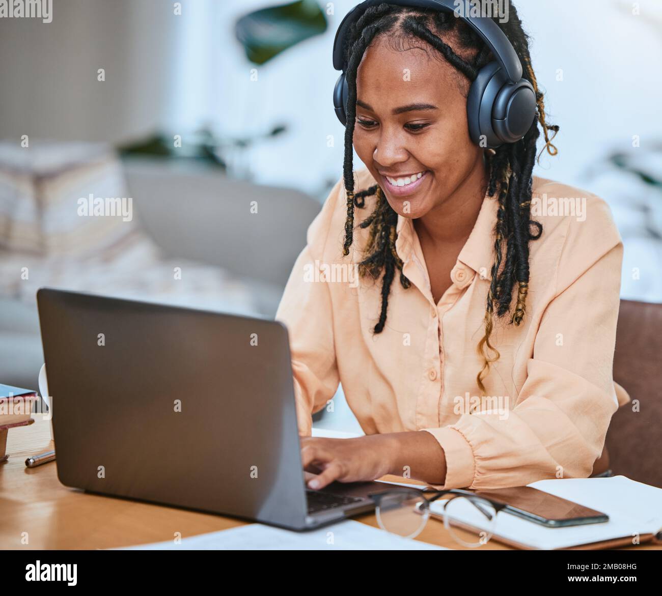Donna nera, notebook e felice con la digitazione di musica online, la comunicazione e-mail o la strategia di pianificazione in ufficio domestico. Ragazza africana, felicità aziendale e. Foto Stock