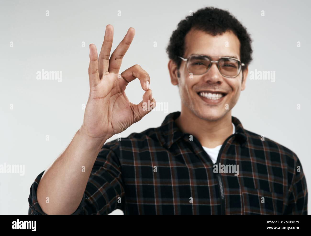 Se nessun altro ti ha detto, credo che tu stia facendo del bene. un bel giovane che mostra il segno ok mentre si trova su uno sfondo grigio. Foto Stock