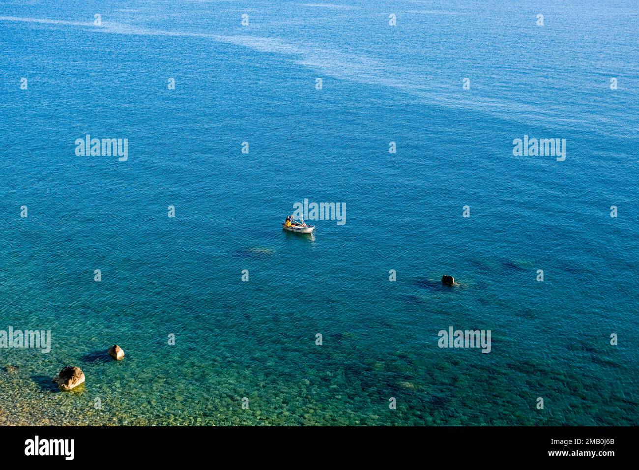 Veduta aerea di un pescatore, che lavora su una piccola barca sul mare di fronte alla cittadina di Castello di Tusa. Foto Stock