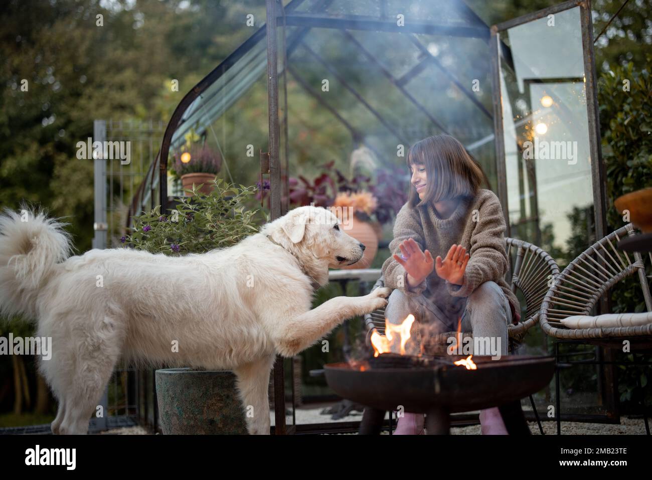 Donna con un cane vicino al fuoco sul cortile Foto Stock