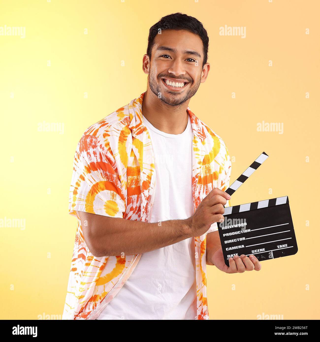 Ritratto, tavola da clapper e uomo in studio isolato su sfondo giallo. Regista, produzione cinematografica e modello maschile felice in tie tinture eleganti o fredde Foto Stock