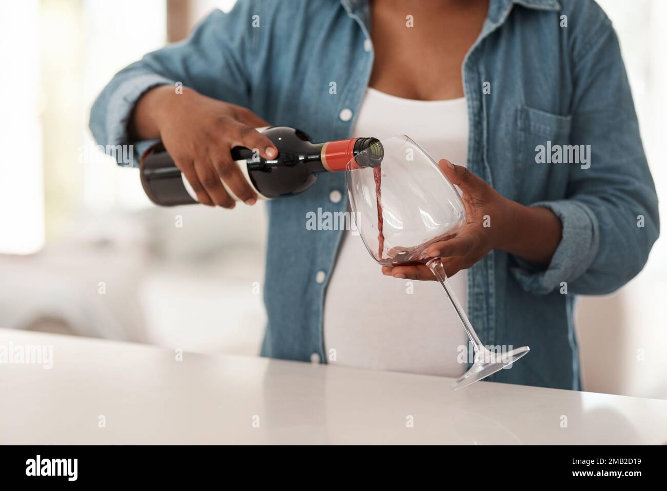 Non essere irresponsabile - il rischio non ne vale la pena. Primo piano di una donna incinta che versa un bicchiere di vino rosso a casa. Foto Stock