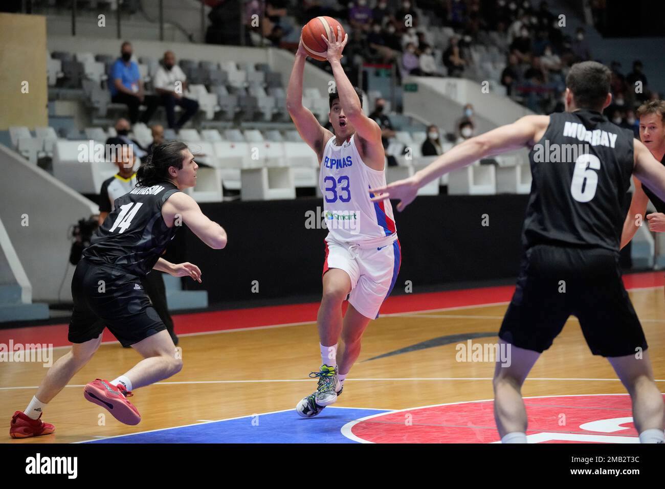 Philippine's Carl Vincent Tamayo, center, drives past New Zealand's Isaac Davidson, left, and New Zealand's Taine Murray during their group phase match at FIBA Asia Cup 2022 basketball tournament in Jakarta, Indonesia, Sunday, July 17, 2022. (AP Photo/Dita Alangkara) Foto Stock