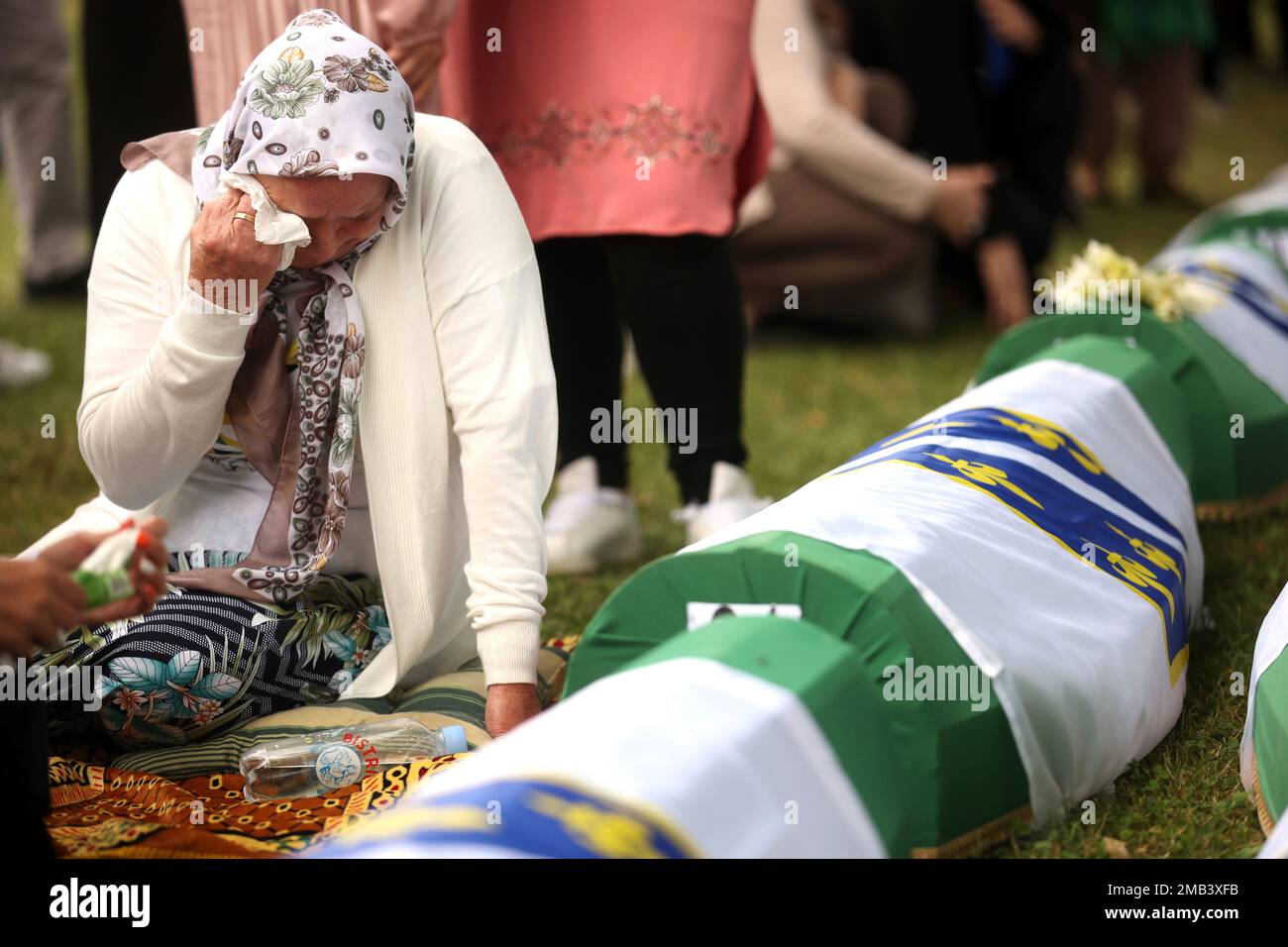 A Bosnian muslim woman mourns next to the coffin containing remains of a family member who is amongst the 50 newly identified victims of the Srebrenica Genocide, in Potocari, Monday, July 11, 2022. Fifty newly identified victims were honored and reburied Monday in Bosnia as thousands gathered to commemorate the anniversary of the 1995 Srebrenica massacre, Europe’s only acknowledged genocide since the Holocaust.(AP Photo/Armin Durgut) Foto Stock