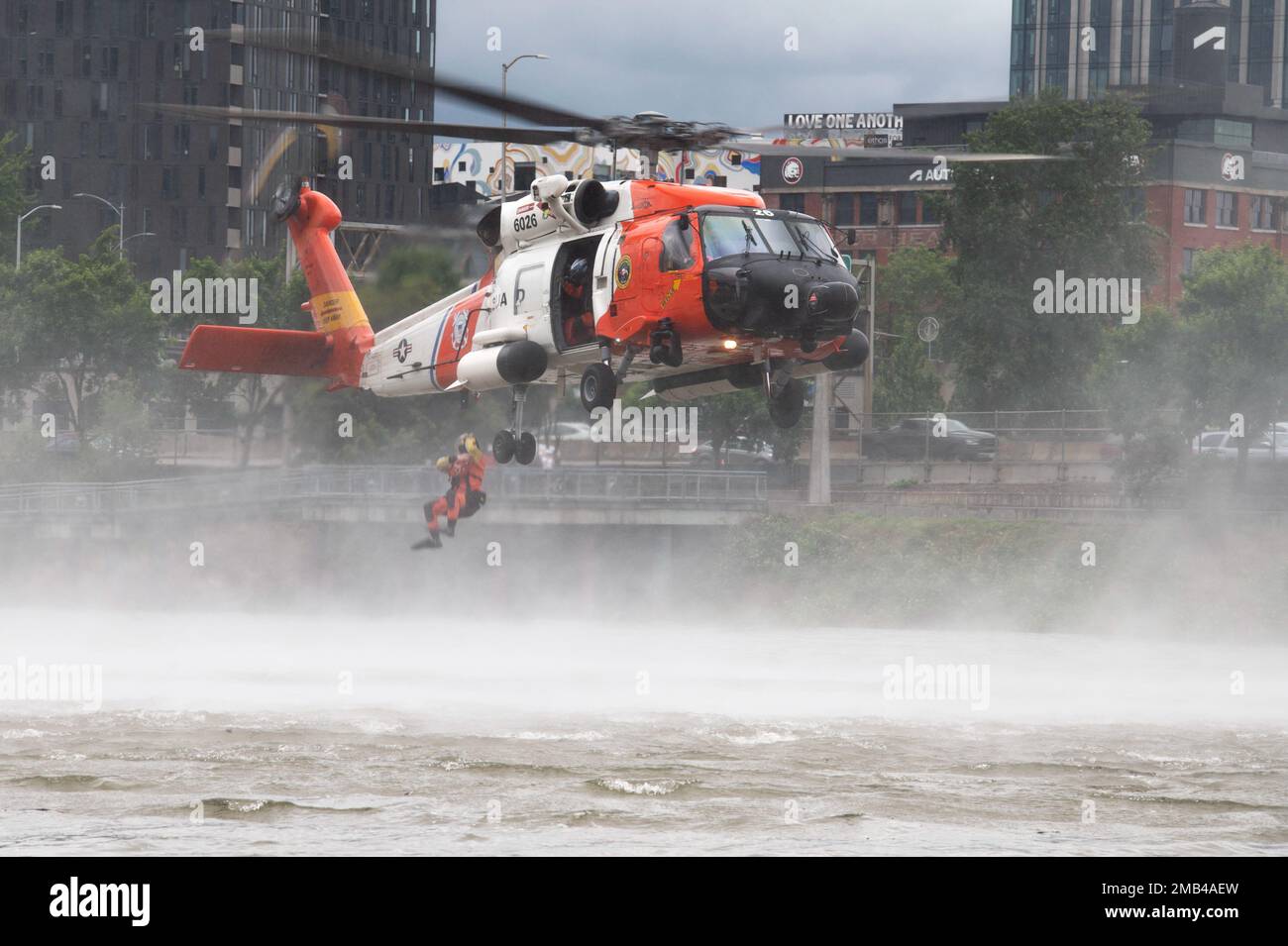 Un tecnico di sopravvivenza dell'aviazione della Guardia Costiera salta nel fiume Willamette da un elicottero Astoria MH-60 Jayhawk a Portland, Oregon, 11 giugno 2022. L'equipaggio ha preformato una dimostrazione di ricerca e salvataggio durante il Portland Rose Festival. Foto Stock
