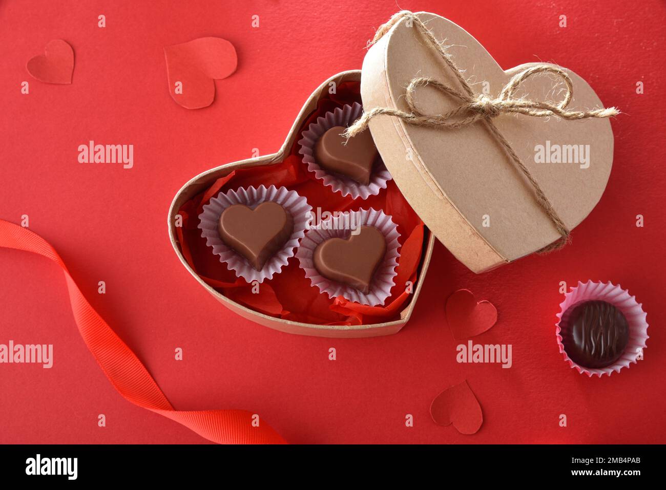 Scatola regalo di cioccolatini di San Valentino su un tavolo rosso decorato  con nastri e cuori. Vista dall'alto Foto stock - Alamy