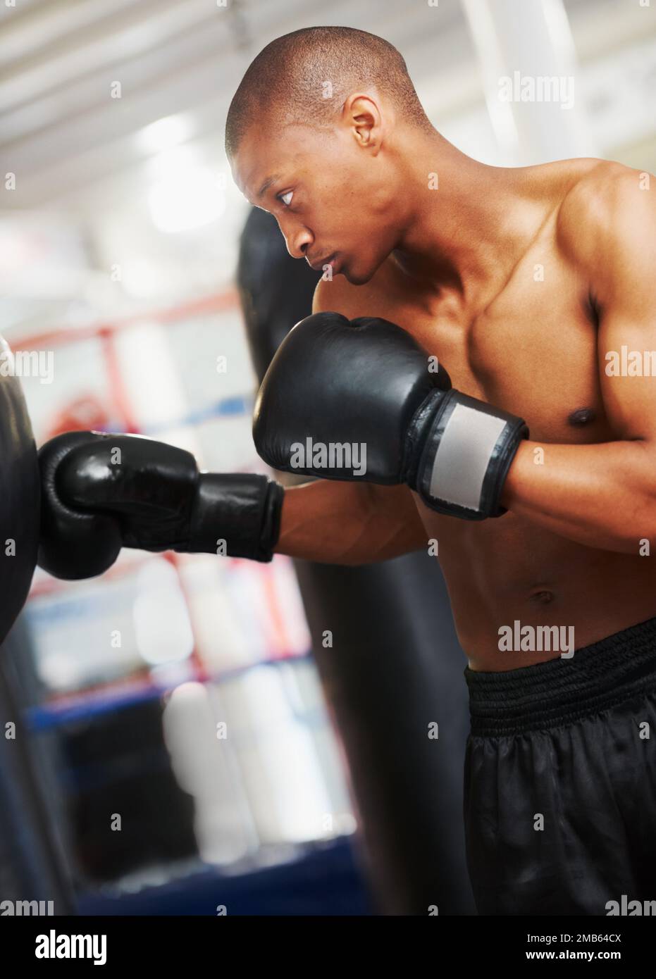 Distruggendo quella palla di punzonatura. Pugile afro-americano che pratica con una borsa da pugno in palestra. Foto Stock